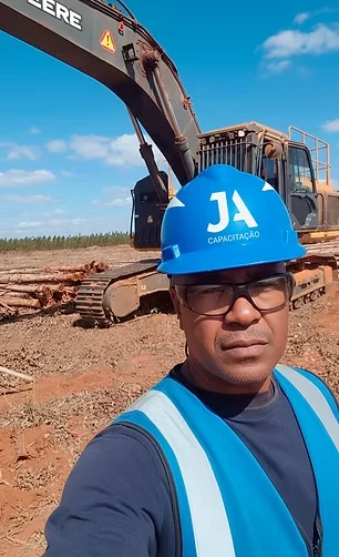 Profissional com o capacete azul da JA Capacitação diante de uma escavadeira, numa frente de trabalho florestal
